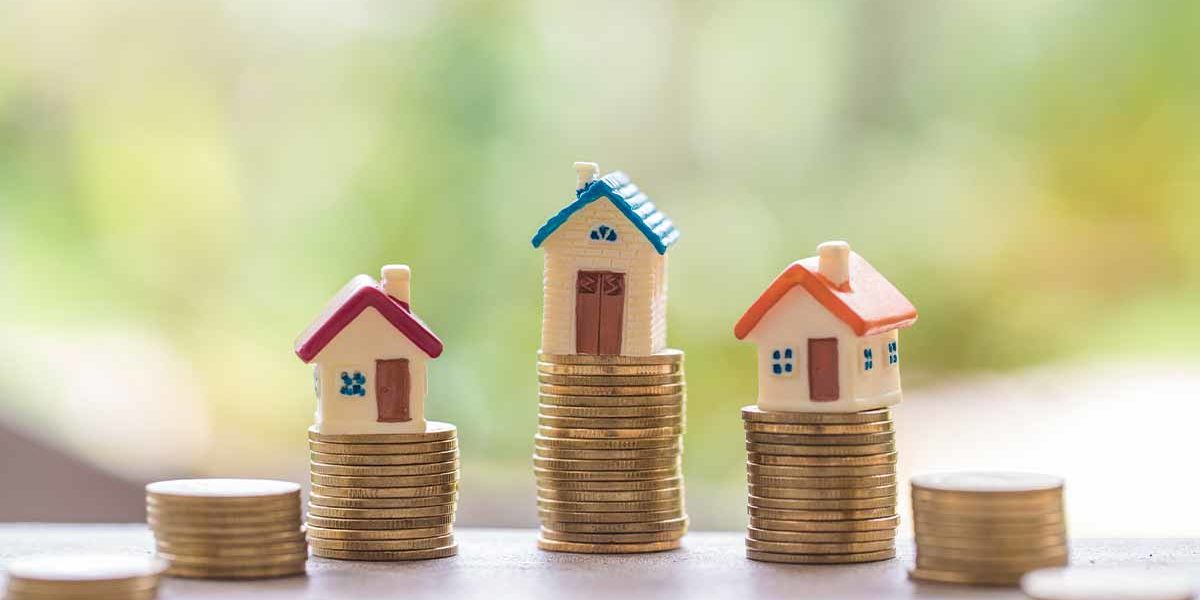 Immobilienfinanzierung Drei Modellhäuschen stehen auf Stapeln von Münzen - Immobilienfinanzierung