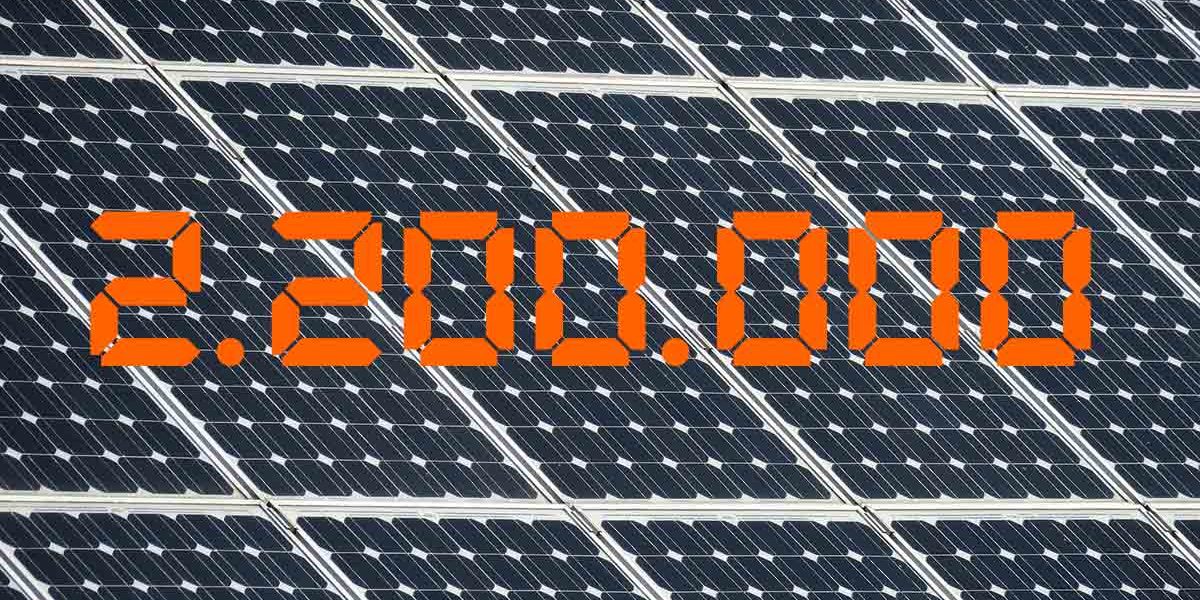 Photovoltaik Die Zahl 2,2 Millionen in Orange vor einem Hintergrund aus Solarpaneelen - Photovoltaik
