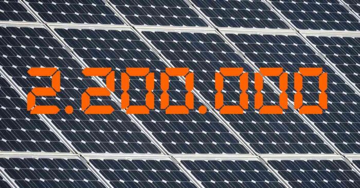 Photovoltaik Die Zahl 2,2 Millionen in Orange vor einem Hintergrund aus Solarpaneelen - Photovoltaik