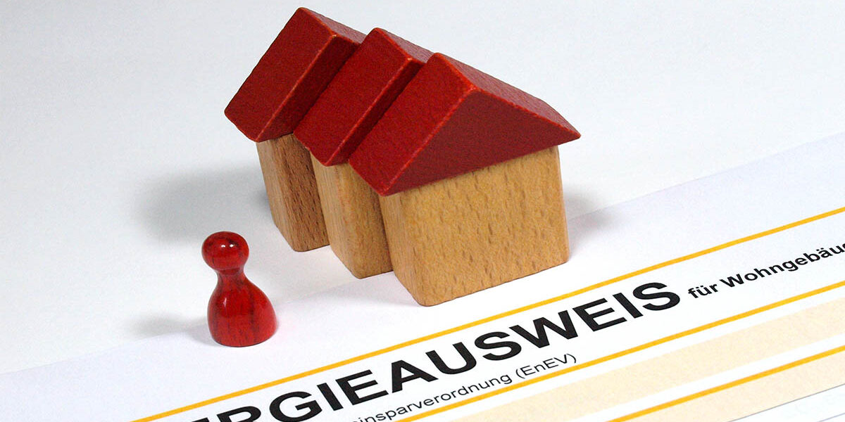 Sanierungspflicht EU Drei Spielzeughäuser und eine Figur und ein Energieausweis - Sanierungspflicht EU