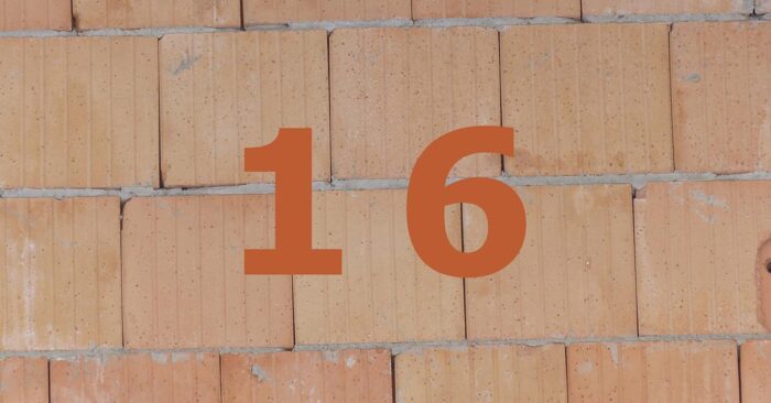 Wohnungsbau Orange Zahl 16 auf gemauerter Häuserwand.