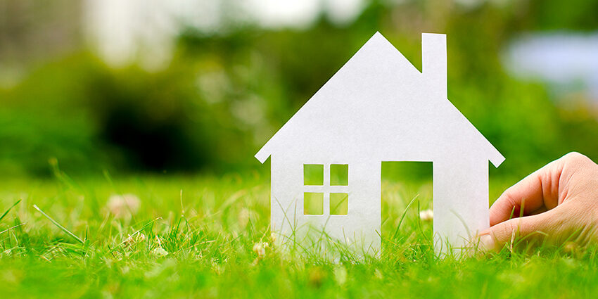 Immobilienkauf Hand hold house against green field; Immobilienkauf