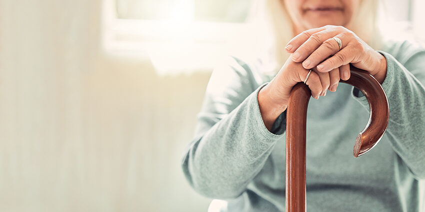 Wohnen im Alter Growing old is inevitable, but growing up is optional. elderly woman resting her hands on her walking stick while relaxing at home; Wohnen im Alter