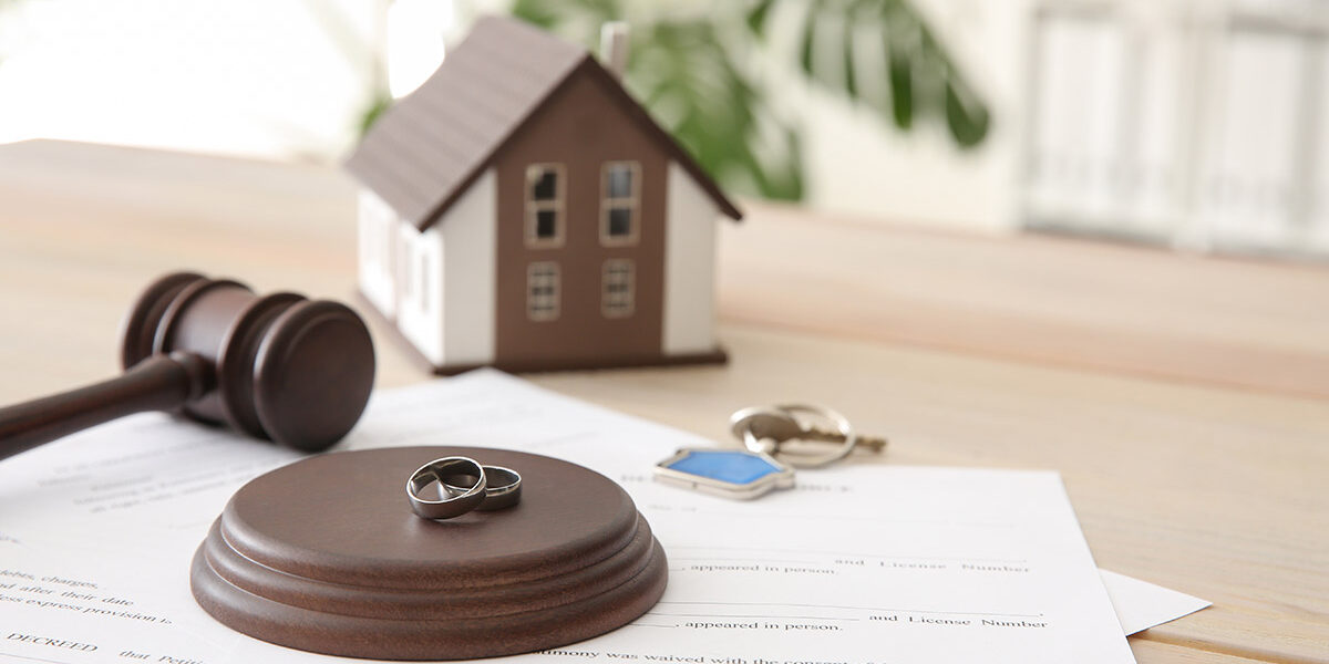 Teilungsversteigerung Richterhammer, mit Eheringen und Papieren auf einem Tisch, dahinter ein Modellhaus und Schlüssel; Teilungsversteigerung