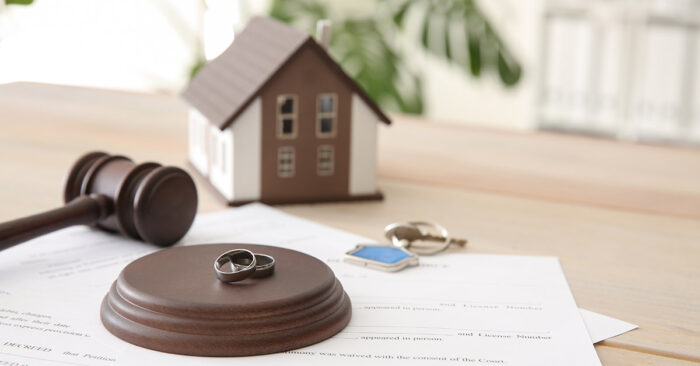 Richterhammer, mit Eheringen und Papieren auf einem Tisch, dahinter ein Modellhaus und Schlüssel; Teilungsversteigerung