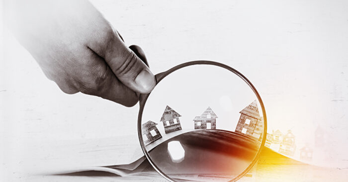 Paper house under a magnifying lens; Immobilienkauf