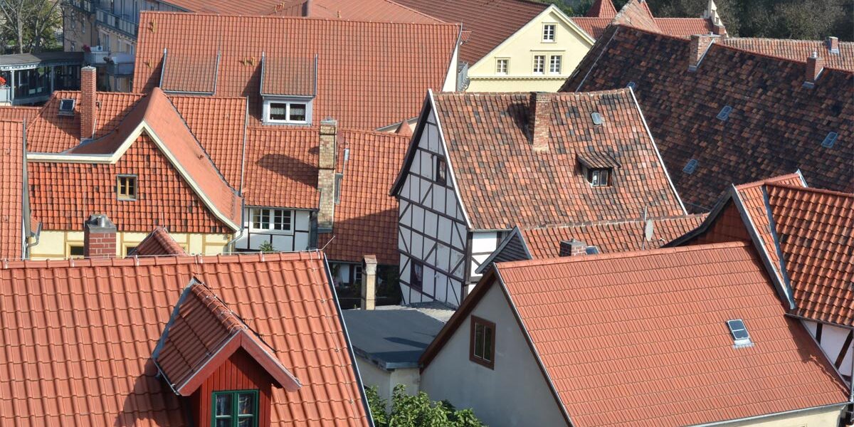 Warum Immobilienkauf jetzt sinnvoll ist? Dächer und Häuserfassaden in einer Einfamiliensiedlung