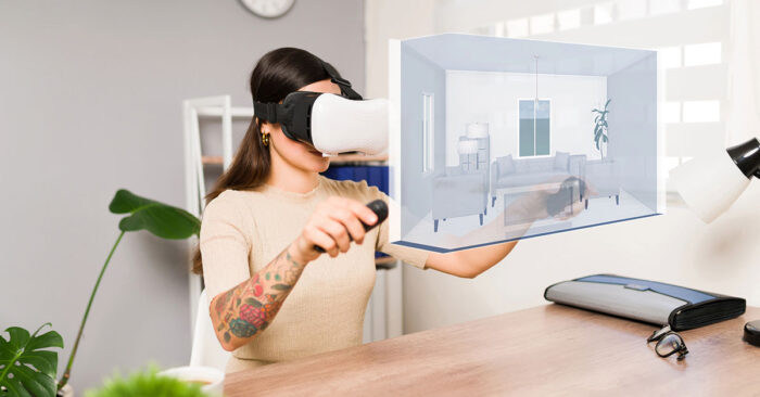 Virtuelle Immobilienbesichtigung Eine Frau mit VR-Brille und jeweils einem Controller in ihren Händen besichtigt in ihrem Wohnzimmer eine Immobilie, die symbolisch vor ihr virtuell dargestellt ist | Virtuelle Immobilienbesichtigung