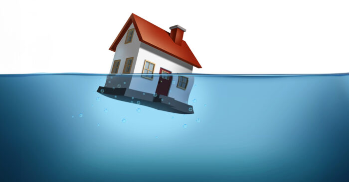 Zwangsversteigerung bei Immobilien vermeiden Ein Haus versinkt im Wasser – eine starke Metapher für Eigentümer in finanzieller Schieflage. Das Bild steht sinnbildlich für den drohenden Verlust der Immobilie durch Zwangsversteigerung und verdeutlicht die Dringlichkeit rechtzeitigen Handelns | Zwangsversteigerung bei Immobilien vermeiden