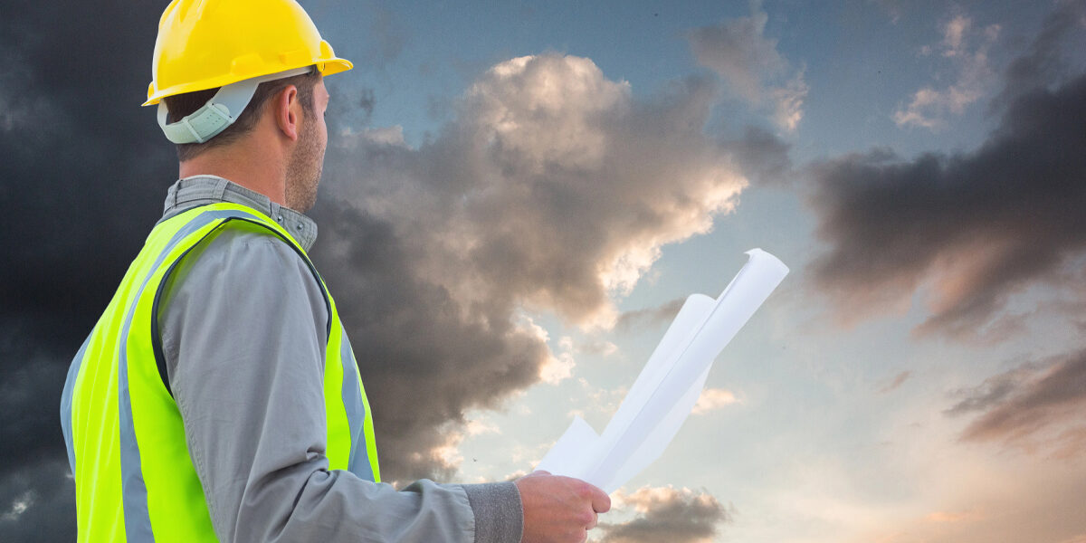 ein Bauarbeiter vor einer Gewitterwand; als symbol für eine Krise im Neubau
