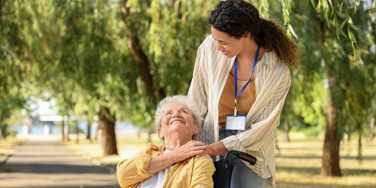 25_08_KW34_Depositphotos_751504074_XL_klein_Copyright_serezniy Eine Seniorin in ihrem Rollstuhl und ihre Pflegerin