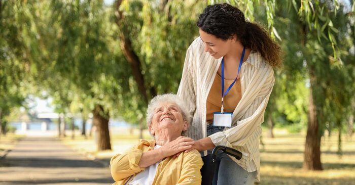 Eine Seniorin in ihrem Rollstuhl und ihre Pflegerin