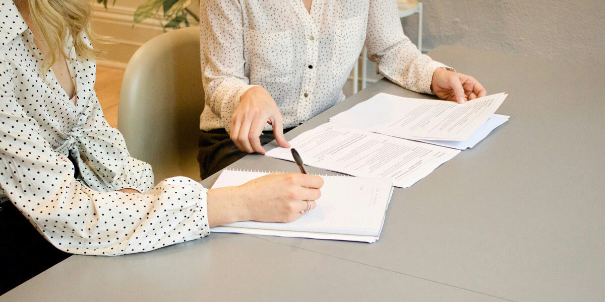 Eine Immobilienkäuferin unterzeichnet den Kaufvertrag bei einer Notarin | Immobilienverkauf