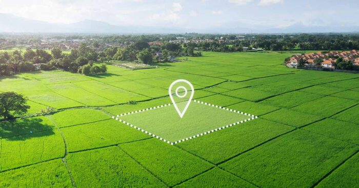 Luftaufnahme eines unbebauten, grünen Grundstücks mit markierter Fläche und Standort-Symbol, das die Entwicklungsmöglichkeiten und den gezielten Verkauf von Bauland veranschaulicht. | Grundstücksverkauf