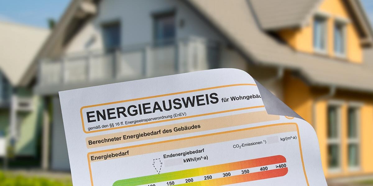 Ansicht eines Energieausweises, im Hintergrund ein Einfamilienhaus | Energieausweis