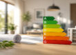 Energieeffizienzskala von A bis G neben Hausmodell und Bauplänen – Symbolbild für den Energieausweis beim Immobilienverkauf.