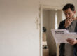 Besorgter Vermieter prüft Mahnung wegen Mietrückstand in beschädigter Wohnung I Mietnomaden